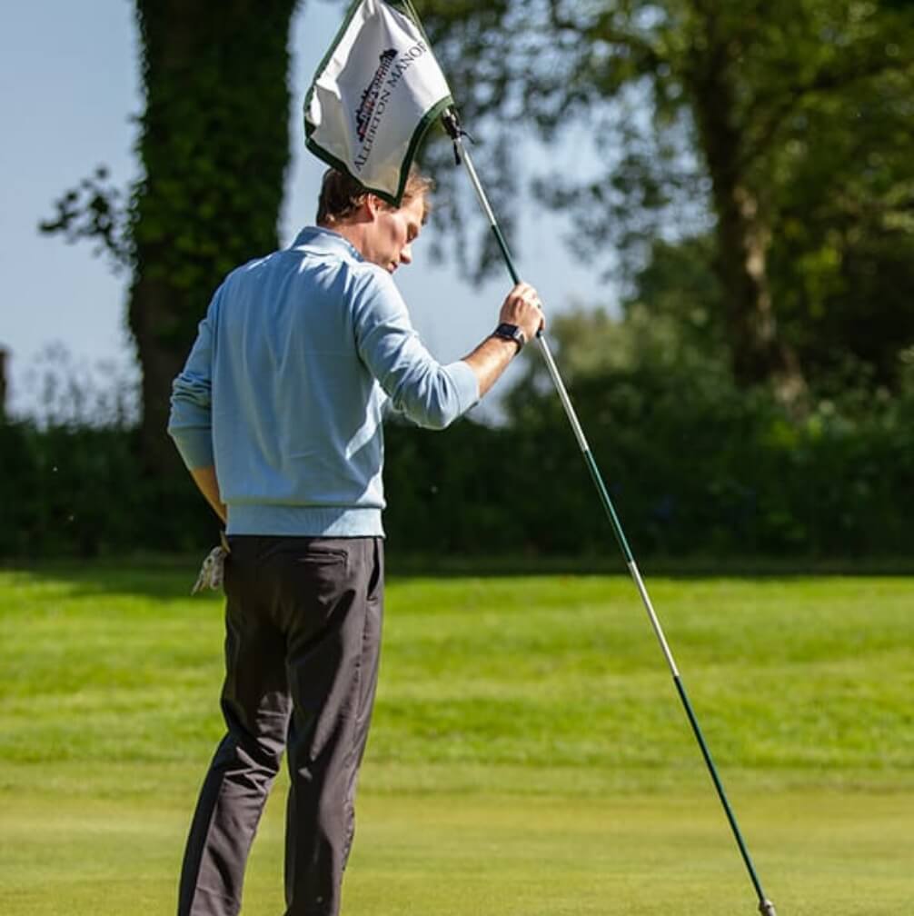 A man planting a golf flag